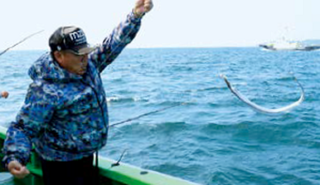 タチウオを海から上に引き上げる男性