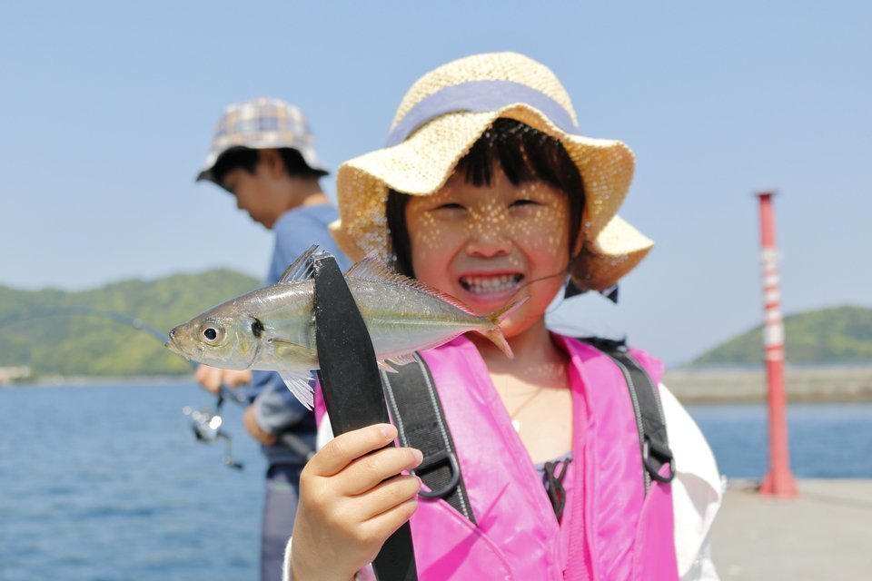 サビキ釣りでアジを釣り上げて笑顔の女の子の写真