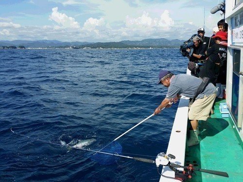 釣り人　男性　タモ　釣り竿　釣船　海　青空　写真