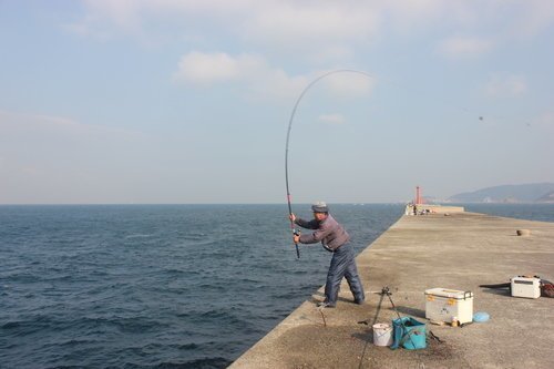 釣り人　男性　釣り竿　埠頭　海　空　クーラーボックス　写真